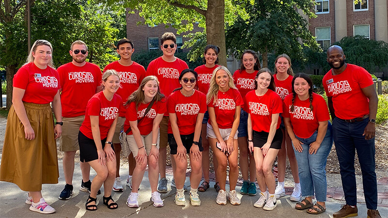 Large group of student ambassadors pose on stairs.